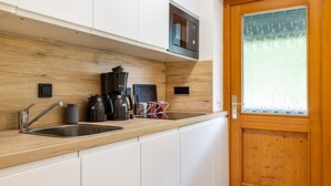 Una cocina con encimera de madera, pileta de acero inoxidable y cafetera.