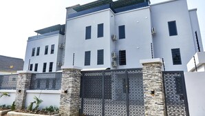 A modern multi-story building with a symmetrical facade, large windows, and a patterned gate.