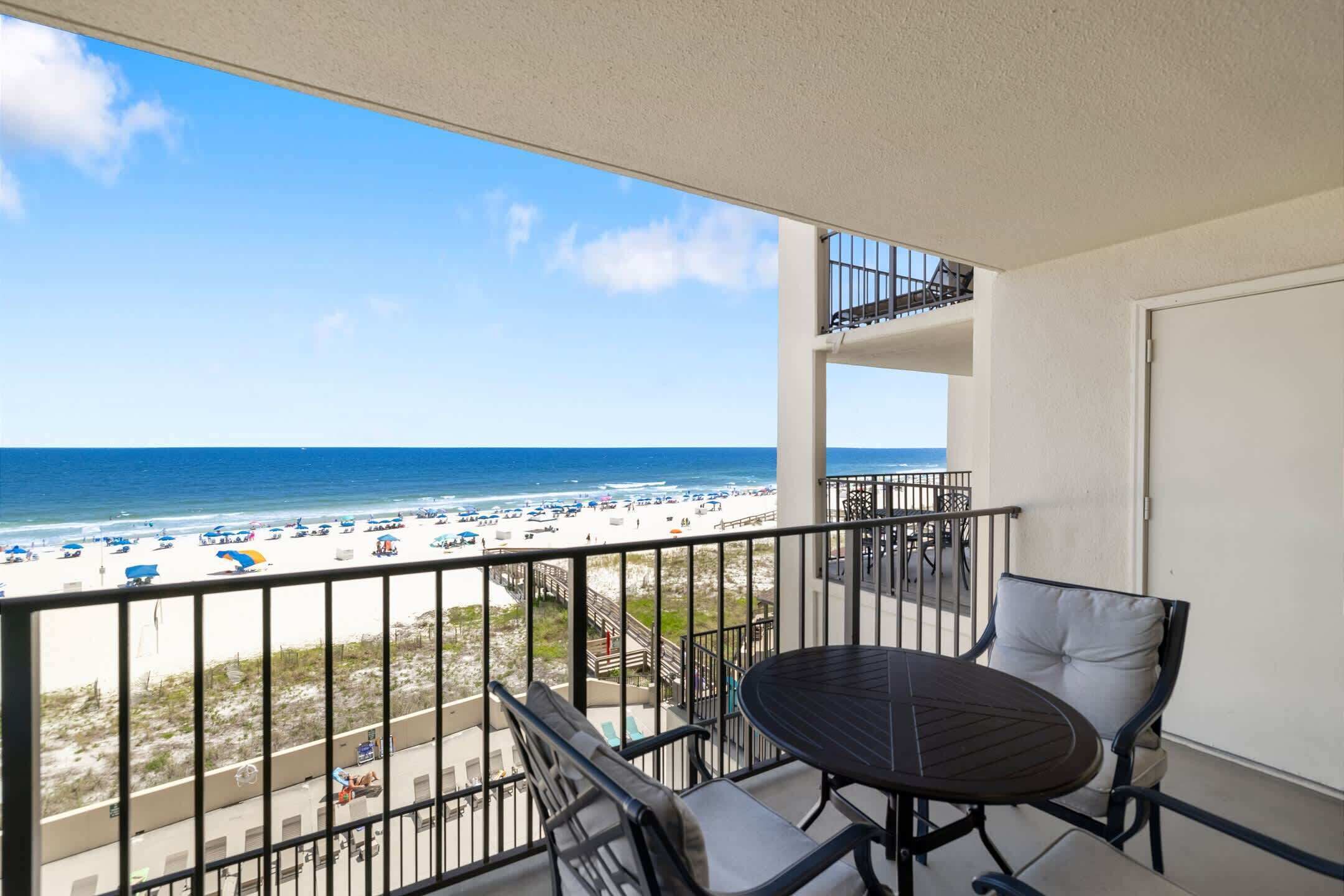 A balcony with a view of the beach and ocean.