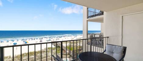 A balcony with a view of the beach and ocean.