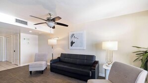 Ein modernes Wohnzimmer mit Deckenventilator, zwei Sofas, einem Sessel und einer Stehlampe.
