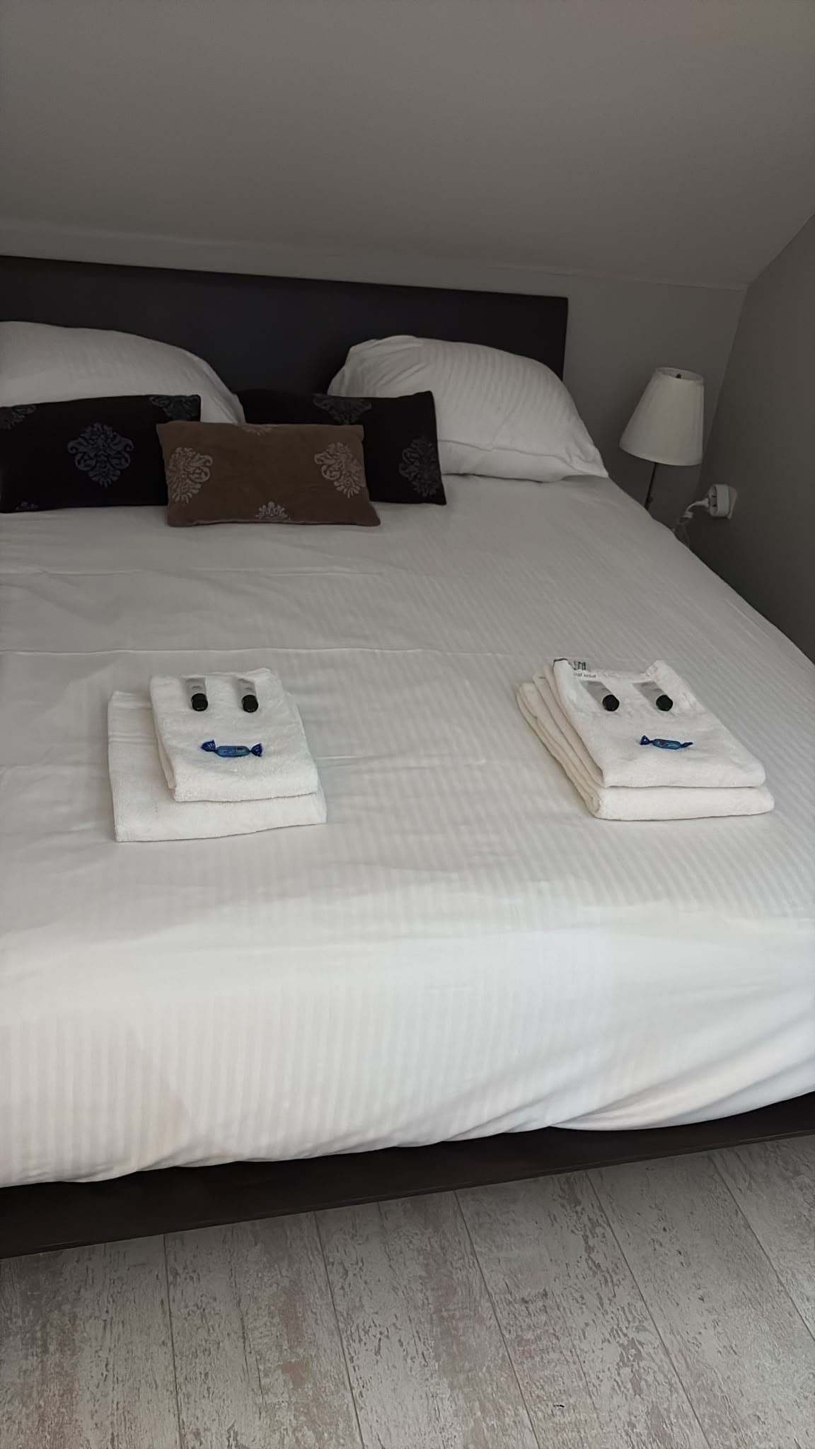 Een opgemaakt bed met kussens en een lamp ernaast.