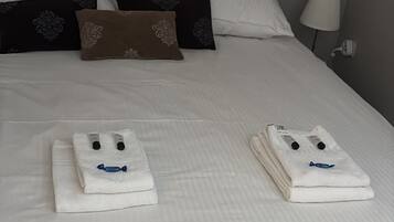 Een opgemaakt bed met kussens en een lamp ernaast.