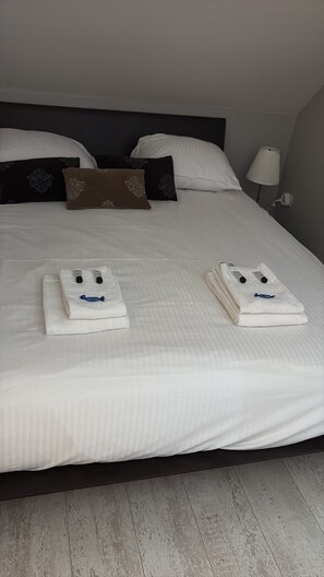 A neatly made bed with pillows and a lamp on the side.