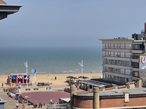 Una platja amb una zona de jocs inflable i colorida, sorra daurada i un edifici amb un cartell gran.