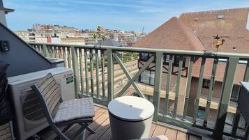 Un balcon donnant sur un paysage urbain, avec une table et deux chaises.