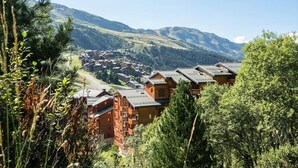 Ein Bergdorf mit Holzhütten und Blick auf ein Tal.