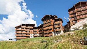 Ein mehrstöckiges Holzgebäude mit Balkonen vor strahlend blauem Himmel.