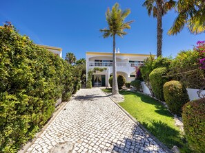 A cobblestone pathway leading to a white building with balconies and palm trees. - Casa Carpe Diem - Amazing villa in Luz (Luz)
