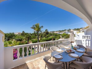 A terrace with a table set for dining, a white railing, and a view of a green landscape. - Casa Carpe Diem - Amazing villa in Luz (Luz)