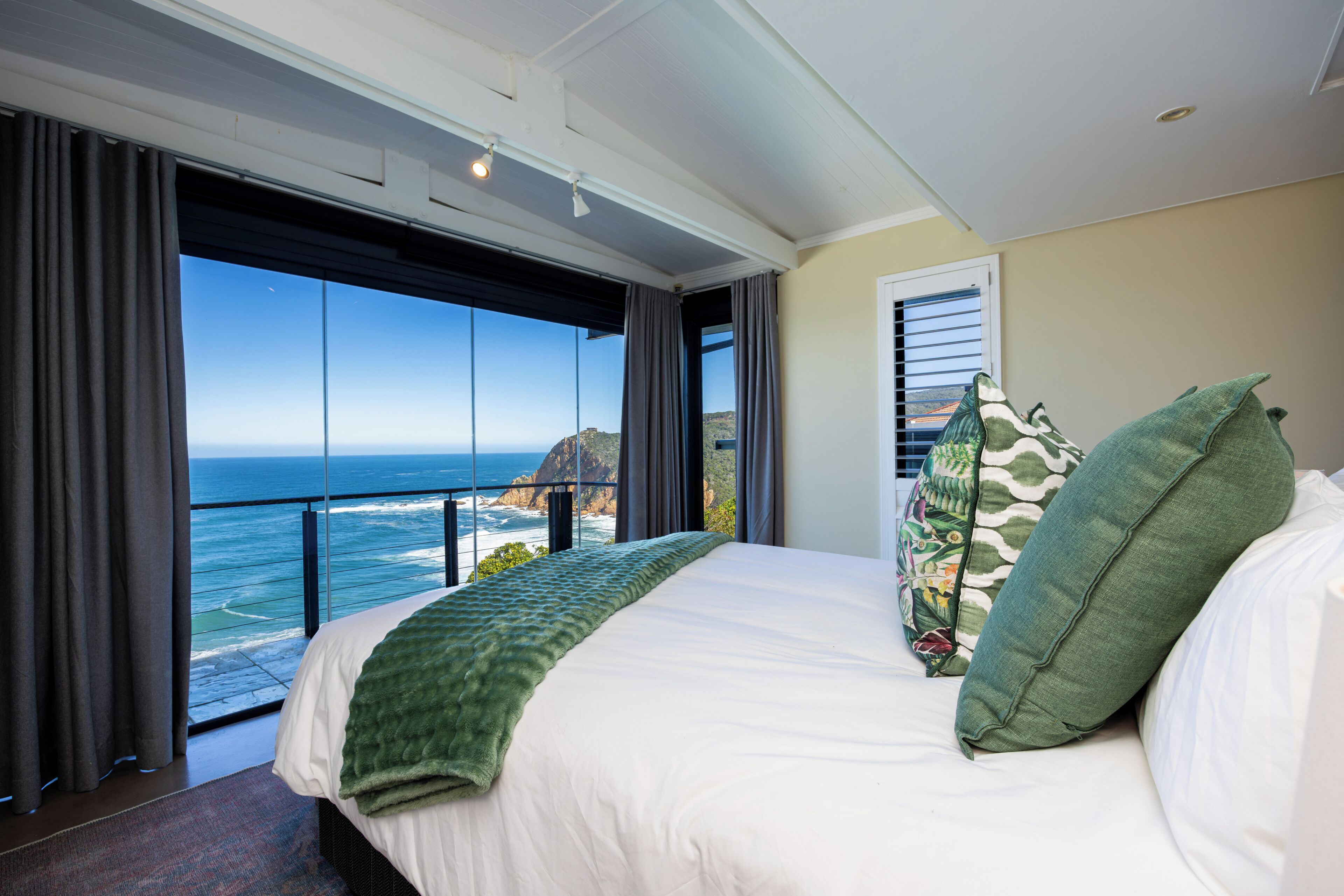 A bedroom with a large bed, a view of the ocean, and a balcony.