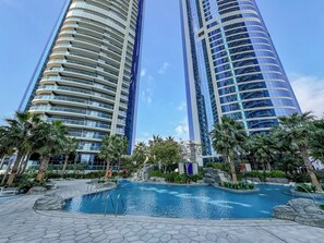 A modern hotel with a pool area, featuring two tall buildings with reflective glass facades. - Amazing 1BR, 10 mins to Burj Khalifa (Dubai)