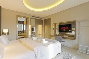 A modern hotel room with a bed, a TV displaying 'NETFLIX,' a desk with a chair, and a walk-in closet. - Amazing 1BR, 10 mins to Burj Khalifa (Dubai)