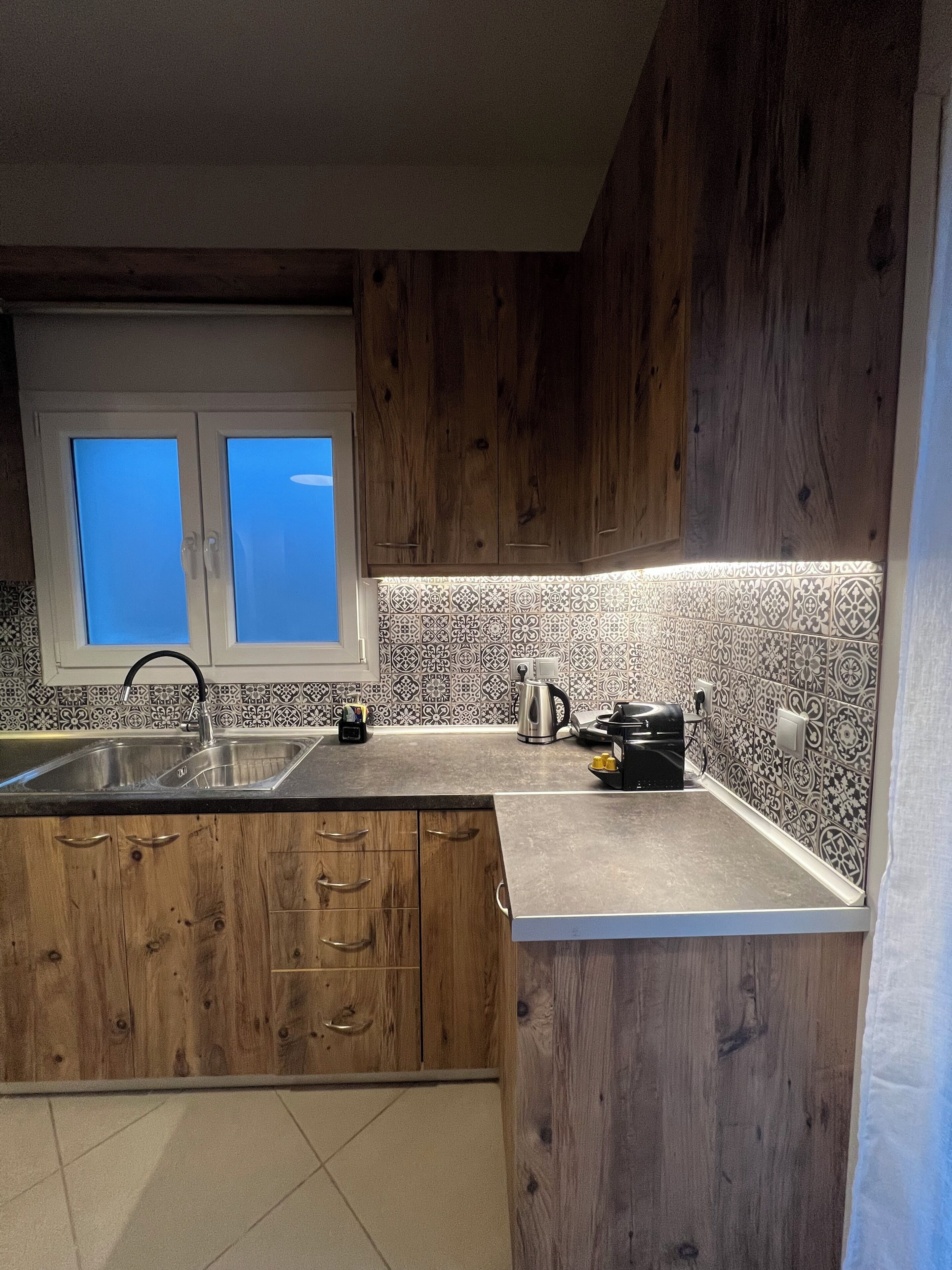 Una cocina con armarios de madera, un lavamanos de acero inoxidable y un salpicadero decorativo.