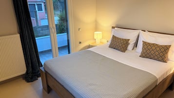 Un dormitorio con cama, mesita de noche, lámpara y vistas a través de un ventanal corredera.