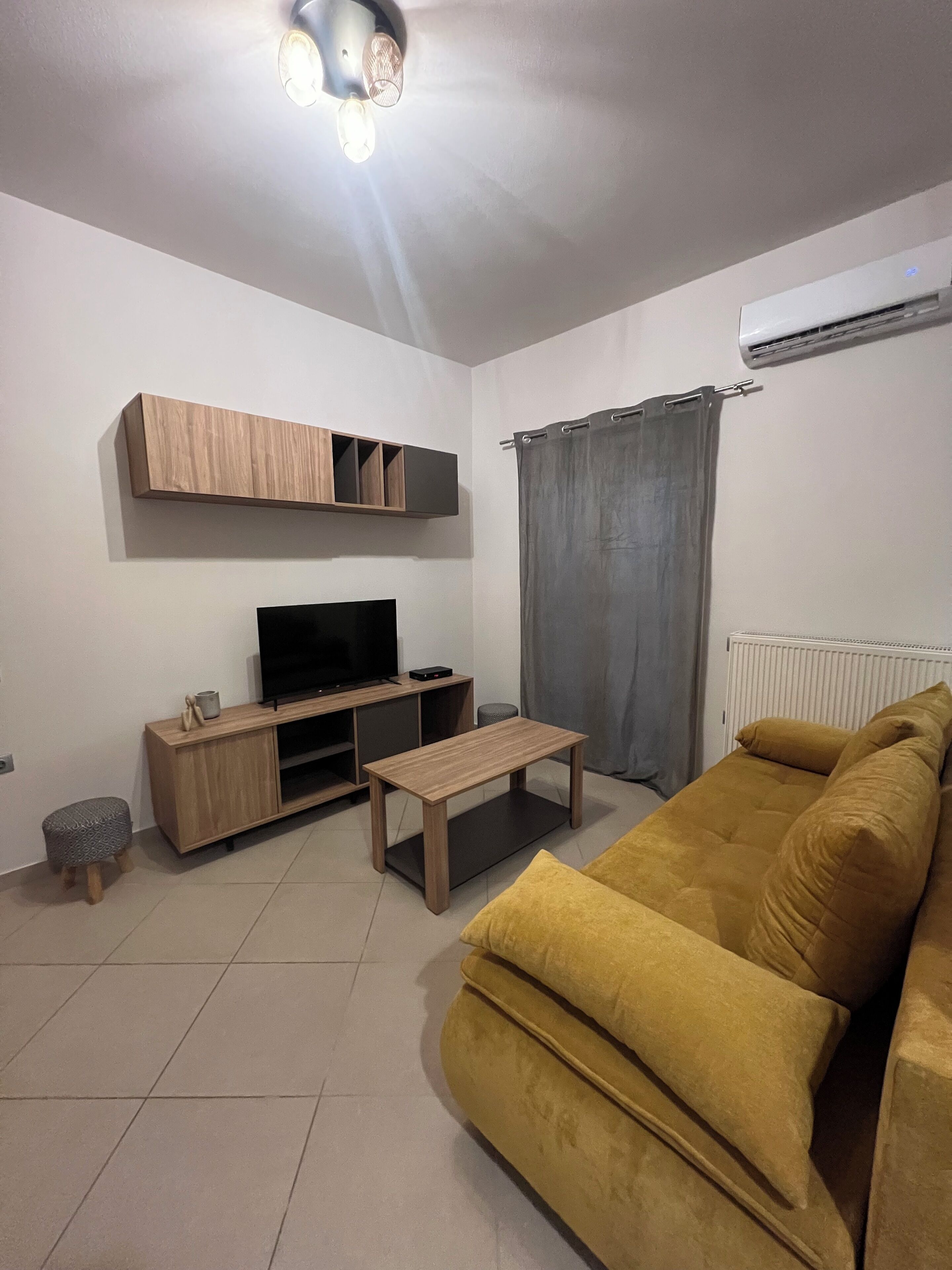 A living room with a sofa, a TV, a coffee table, and a wall-mounted shelf.
