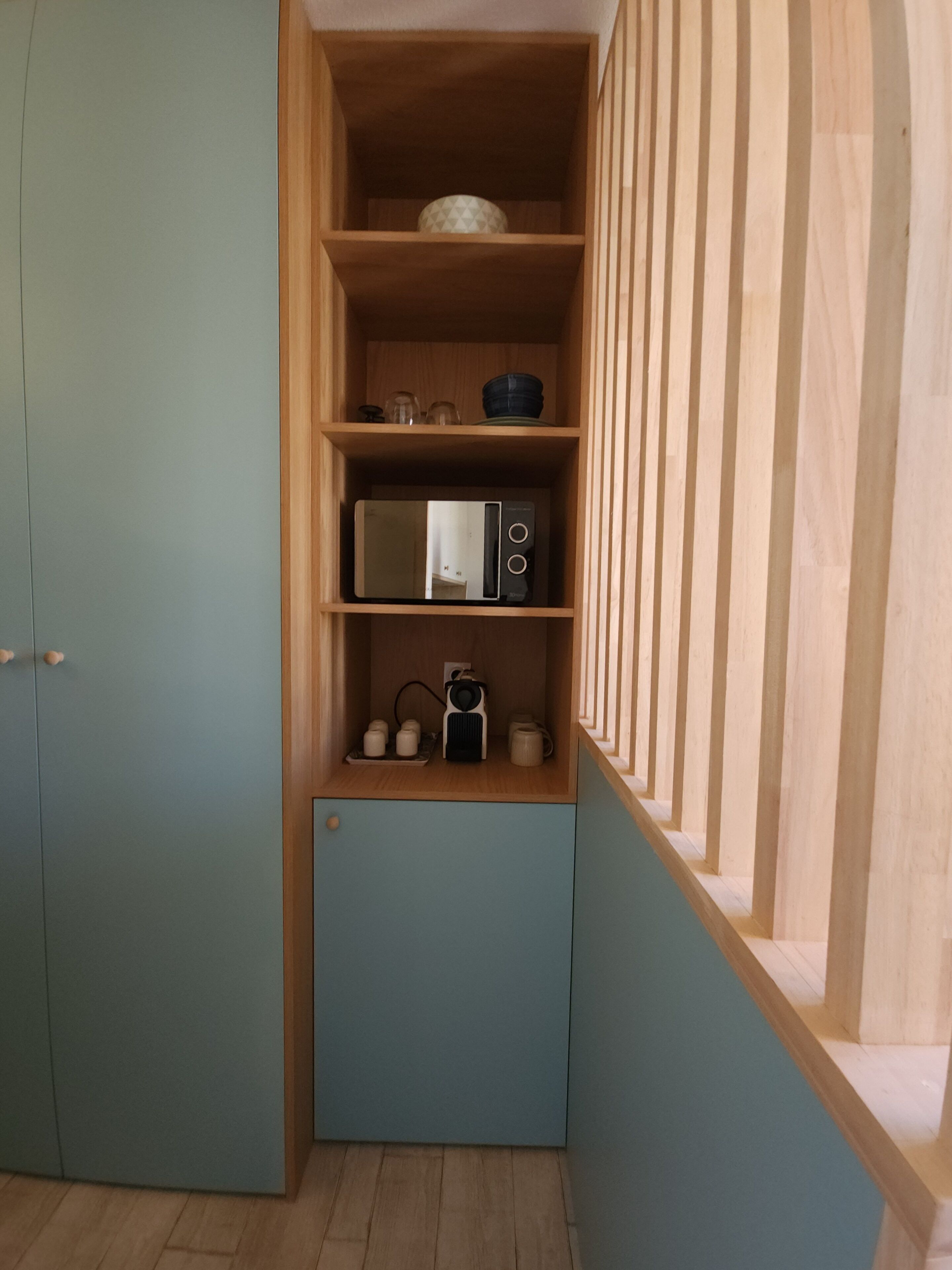 Cocina compacta con microondas, hervidor y estanterías.