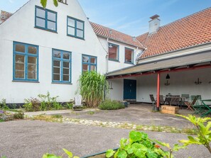 Ein weißes Gebäude mit blauen Fensterrahmen und einem roten Ziegeldach.