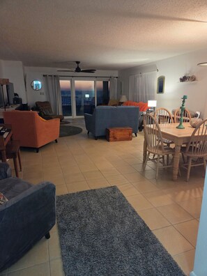 Ein Wohnzimmer mit einer Couch, Stühlen, einem Esstisch und Blick durch eine Schiebetür.
