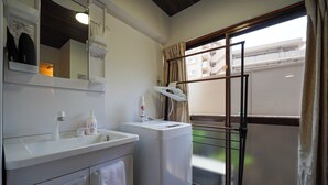 A bathroom with a sink, mirror, and a window with a view of a balcony. - Guest House WASSO (京都市伏見区深草下川原町)