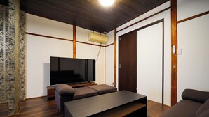 A modern living room with a flat-screen TV, a sofa, a coffee table, and a wooden floor. - Guest House WASSO (京都市伏見区深草下川原町)