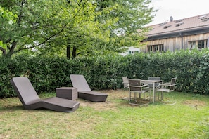 Ein Außenbereich mit Korlounge-Stühlen und einem Metalltisch.