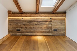 A room with wooden flooring, a sloped ceiling with exposed beams, and a skylight.