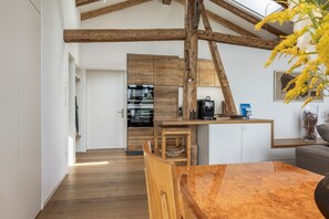 Eine moderne Küche mit Holzbalken, einem eingebauten Ofen und einer Kaffeemaschine.