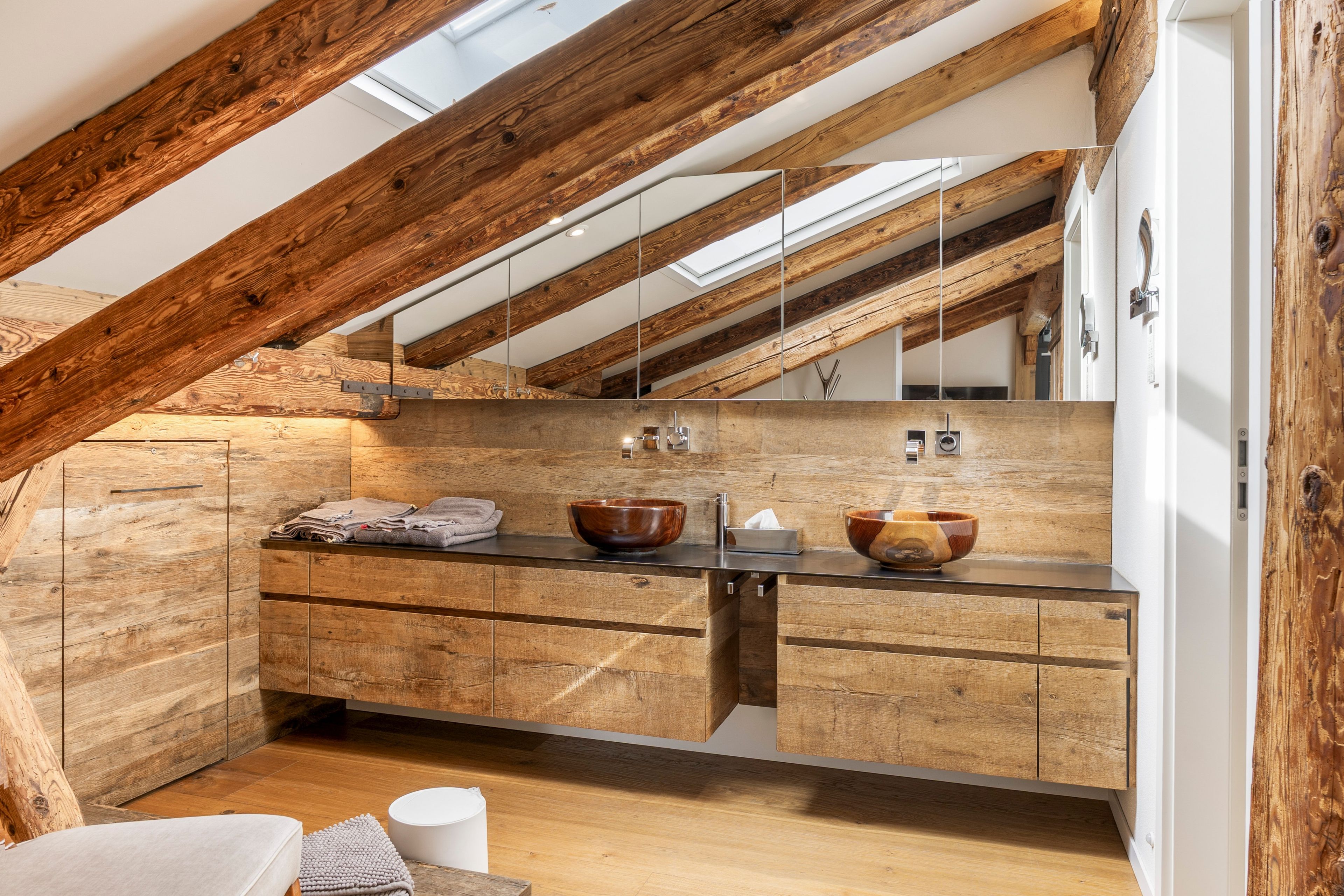 Een moderne badkamer met een houten wastafel, twee houten kommen en een spiegel.