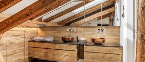 Een moderne badkamer met een houten wastafel, twee houten kommen en een spiegel.