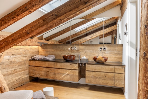 A modern bathroom with a wooden vanity, two wooden bowls, and a mirror.