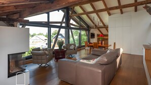 A spacious living area with a large window, a sofa, a chair, and a dining table.