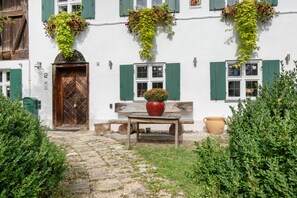 A traditional building with a wooden door, green shutters, and flower boxes on the windows.