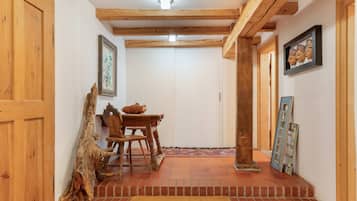 Interior de madeira com mesa de jantar, cadeiras e decoração rústica.