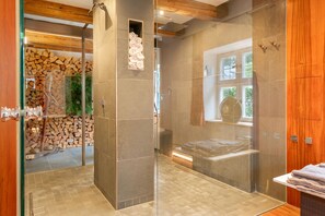 Ein modernes Badezimmer mit einer gläsernen Dusche, einer Holzbalkendecke und einer Steinwand.