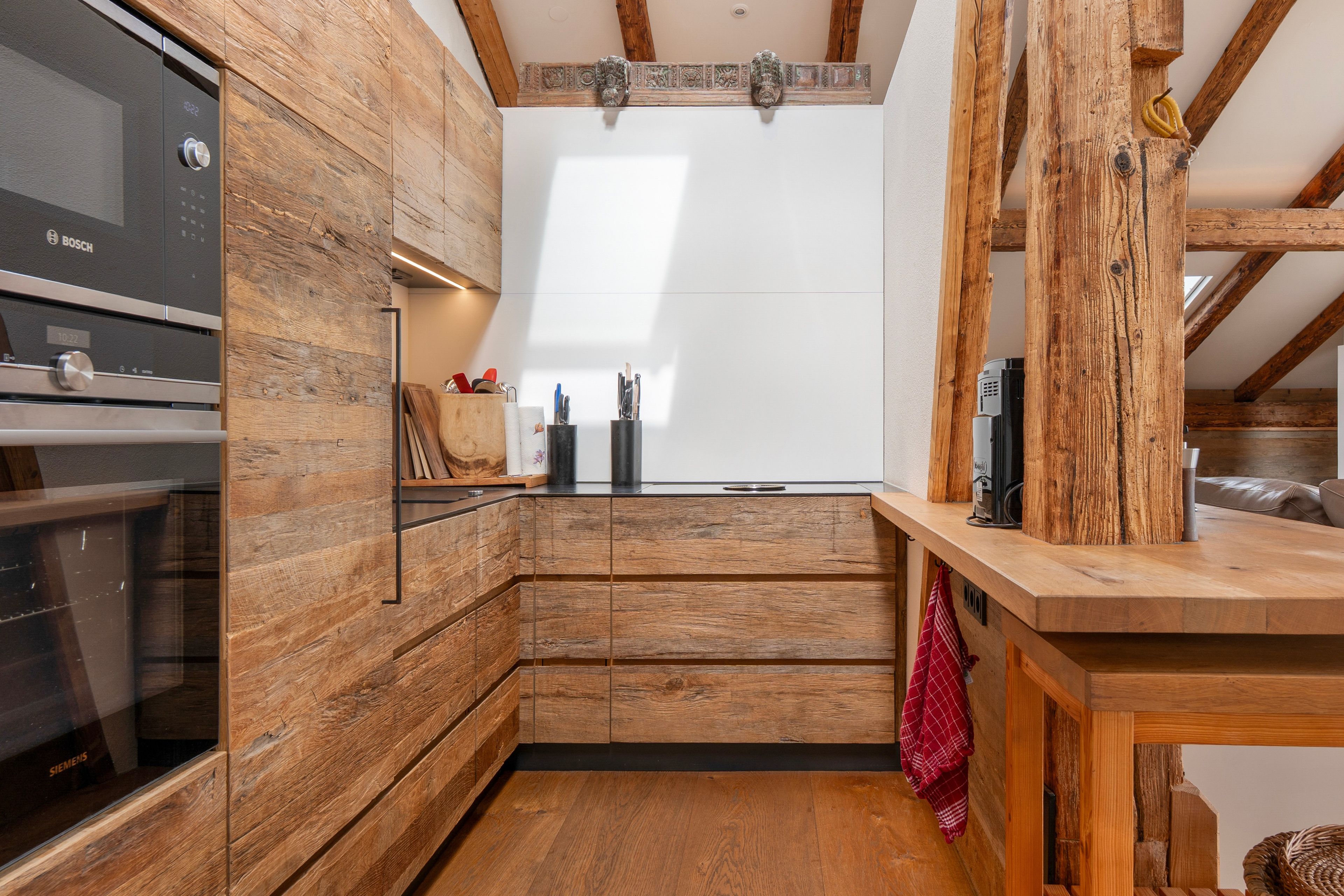 A compact kitchen with wooden cabinetry, a Bosch oven, and a window above the sink.