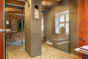 Ein modernes Badezimmer mit einer gläsernen Duschkabine, einer Holzbodenverkleidung und einer Steinwand.