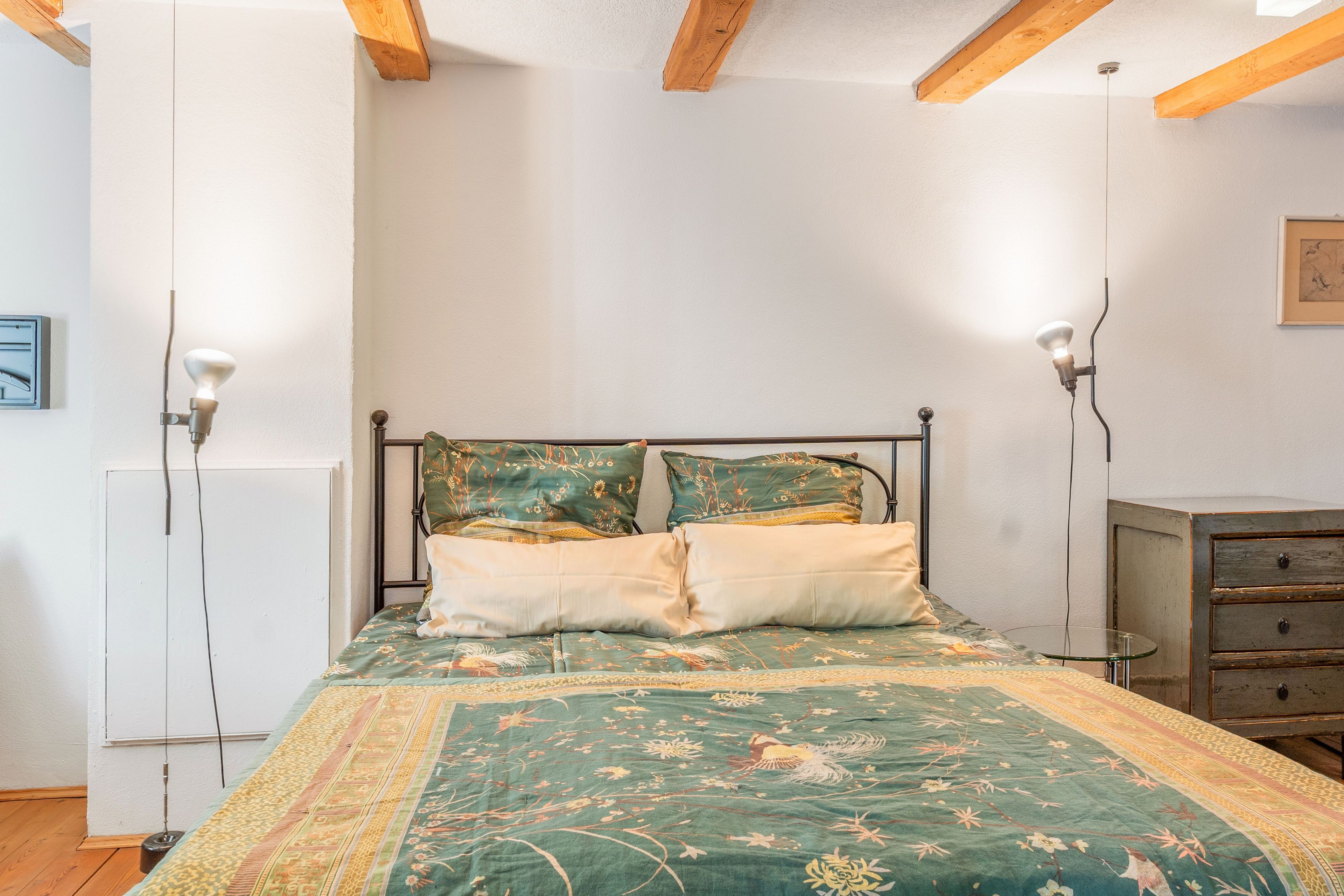 A bedroom with a bed, two bedside lamps, a dresser, and a framed picture on the wall.
