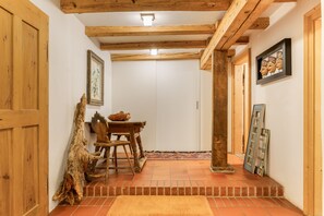 Ein Flur mit Holzbalken, einem rustikalen Tisch, Stühlen und einem Teppich.
