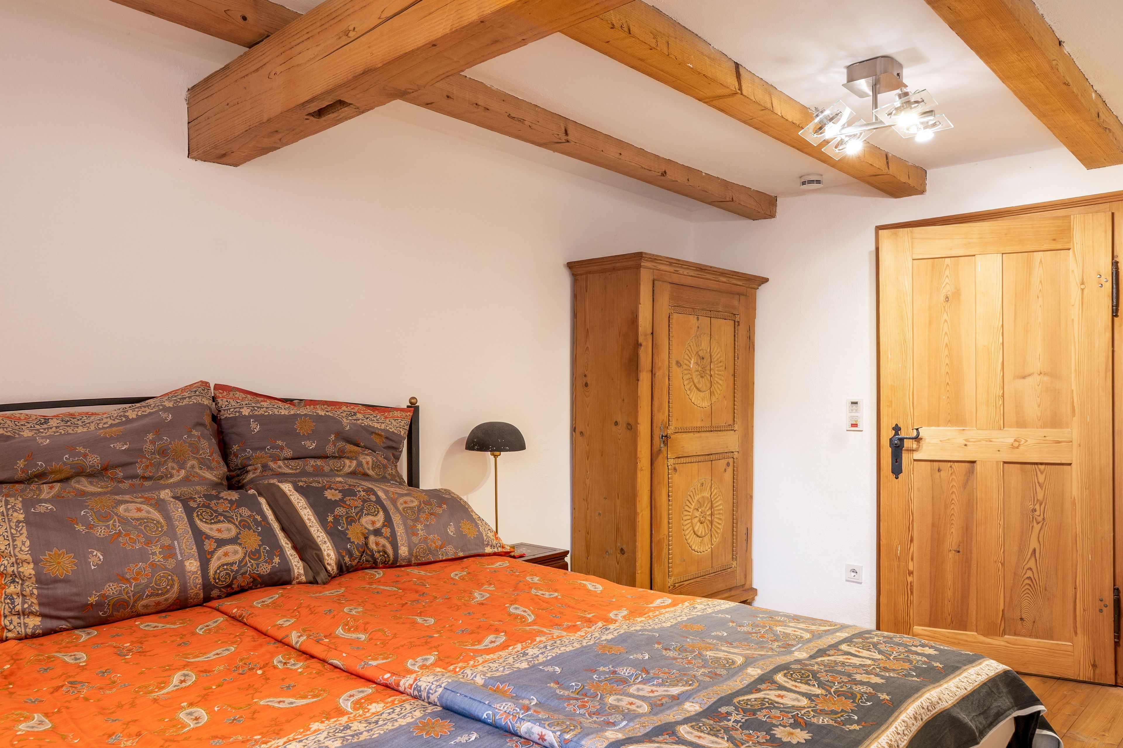 Ein Schlafzimmer mit einem Bett, einem Holzschrank und einer Tür.