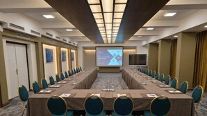 A conference room with a long table, chairs, a screen, and a projector. - Hotel Bellevue (Ilinden)