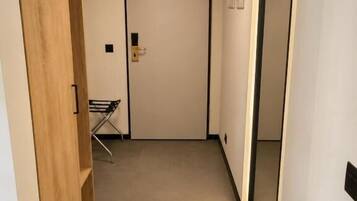 Un pasillo estrecho con un armario de madera, una puerta con manija y un pequeño perchero con objetos.