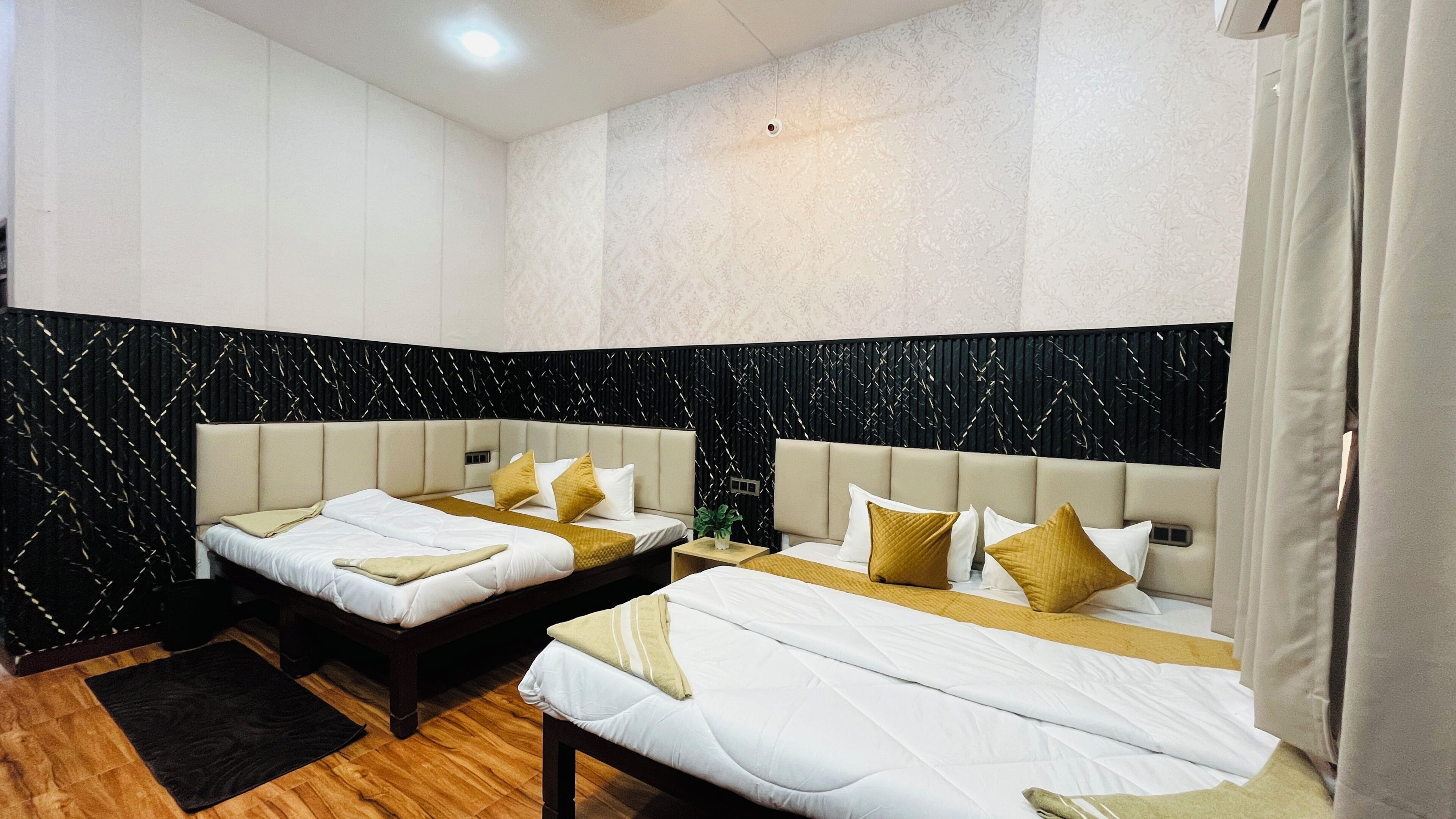 Habitación de hotel con dos camas, una pared estampada en blanco y negro y suelo de madera.