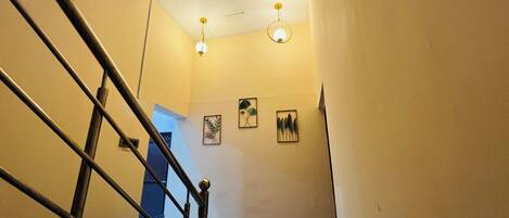 A staircase with a handrail, a ceiling light fixture, and three framed wall decorations.