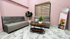Un salon avec un canapé gris, une table basse ronde, un globe terrestre et une plante en pot.
