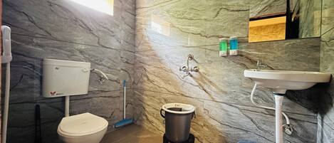 Un baño con inodoro, lavamanos, ducha y pared de mármol.