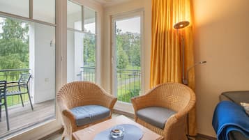 Un balcon avec des fauteuils en osier, une table et une vue sur la verdure.