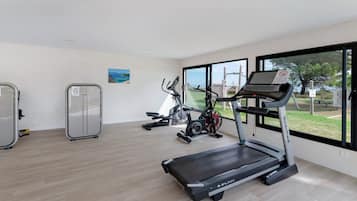 A gym with cardio machines, a weight bench, and a large window with a view of the outdoors.