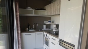 A compact kitchen with a refrigerator, oven, sink, and coffee maker.