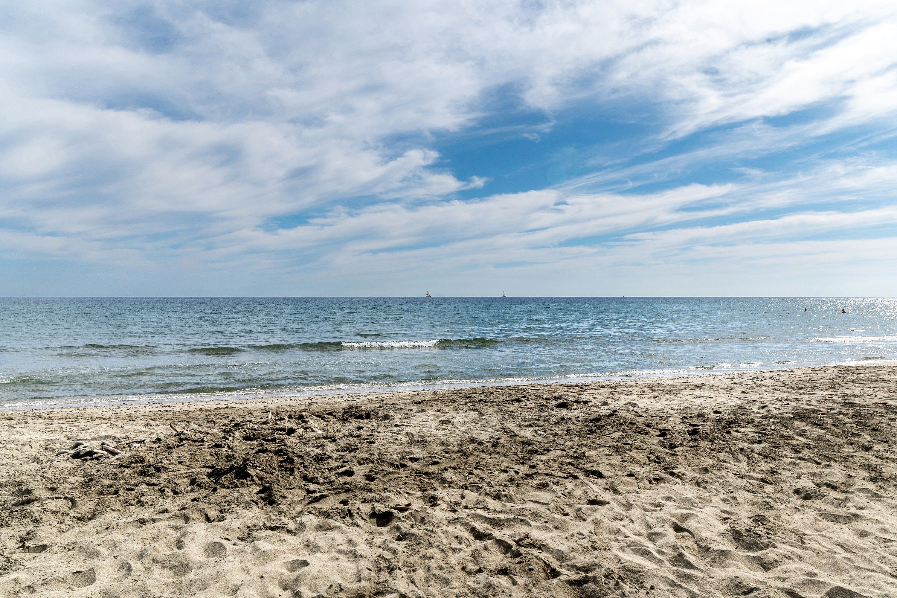 Een strand met een zandstrand en de oceaan op de achtergrond.